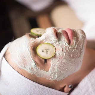 mujer con crema y pepino en los ojos tratamiento facial